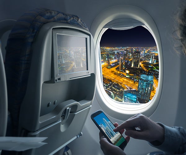 image of a person using their phone on an airplane near the window