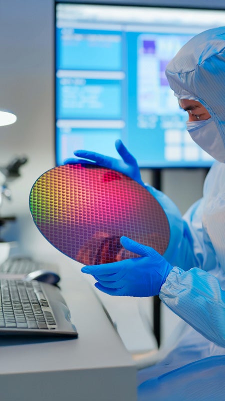 Technician holding a wafer in a cleanroom