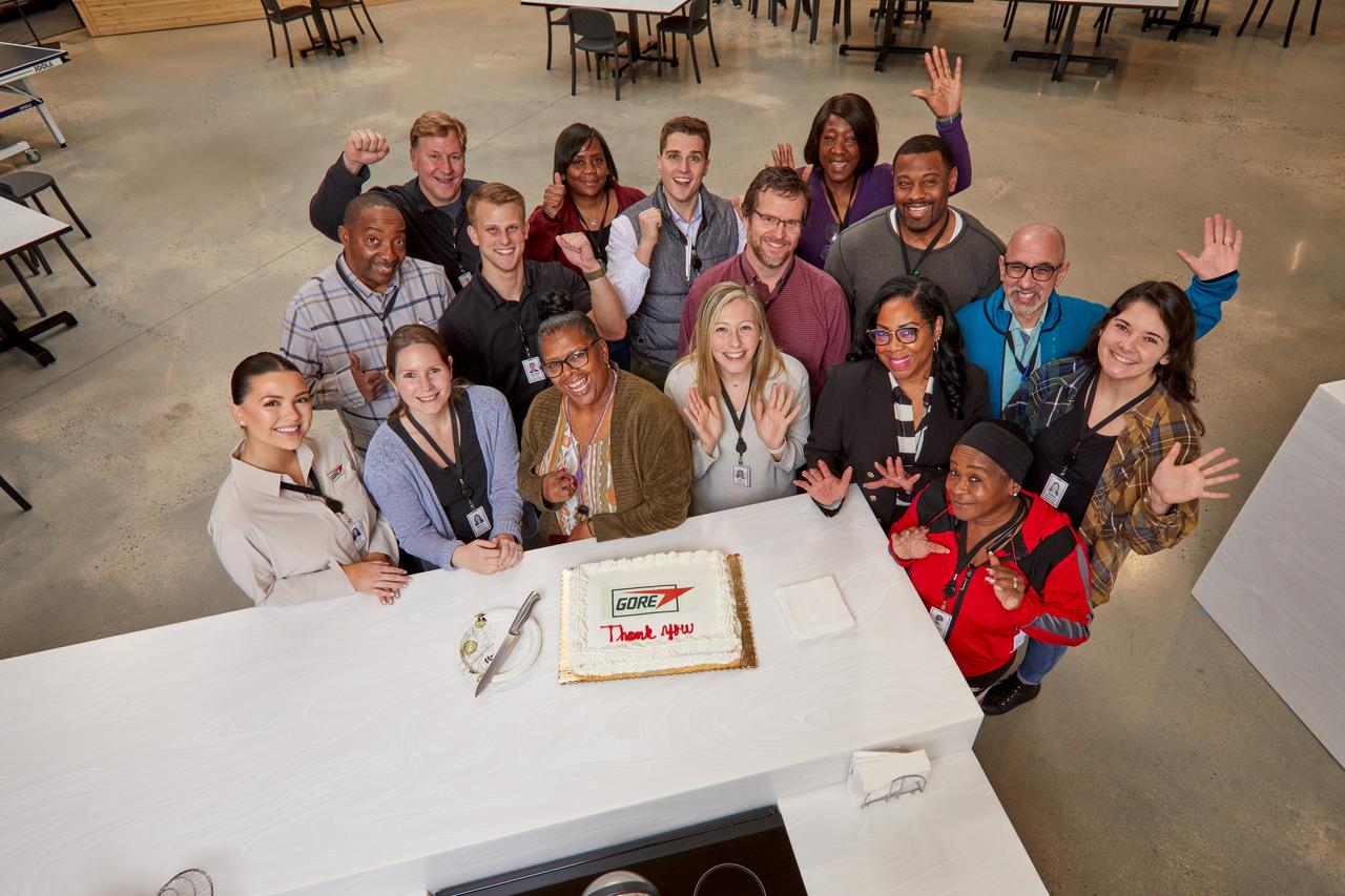 group of associates standing by a Gore thank you cake