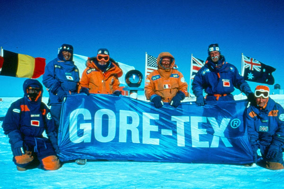 group photo of people in antarctica with winter gear and a gore-tex banner