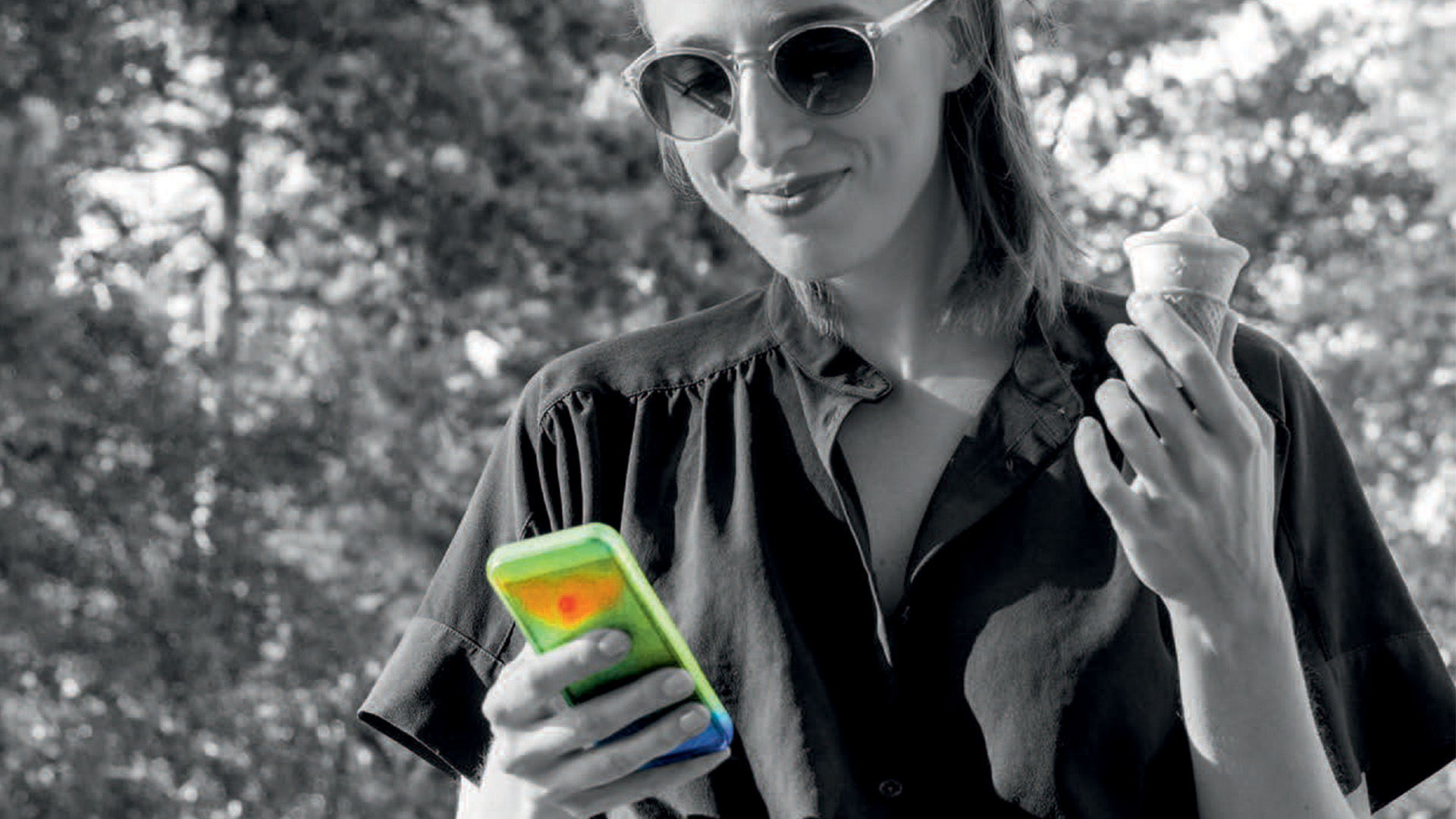 Woman looking at her mobile phone while eating an ice cream cone