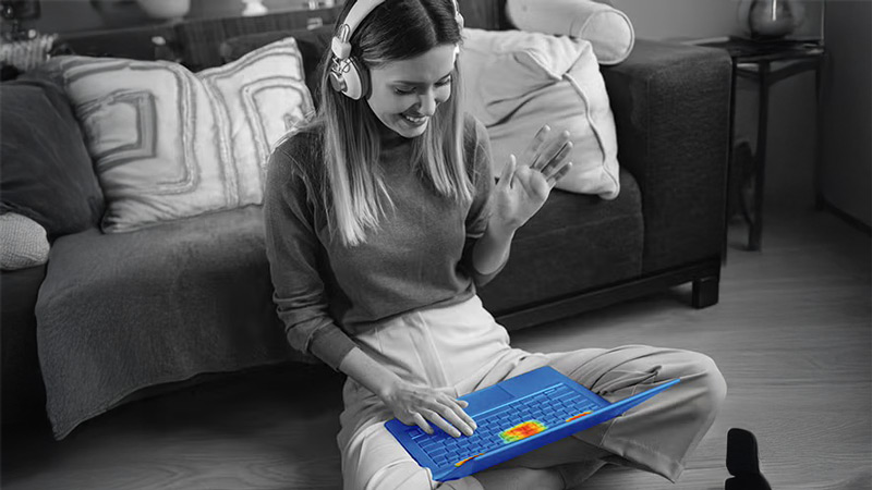 A black and white photo of a woman viewing a laptop. The laptop is stylized to show a heat map.