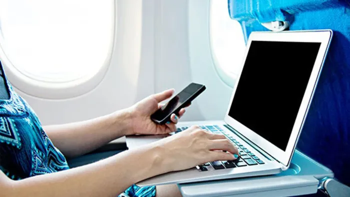 Passenger using laptop and cell phone on airplane