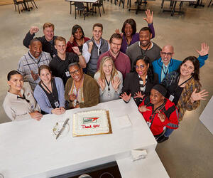 A group of Associates standing around a cake
