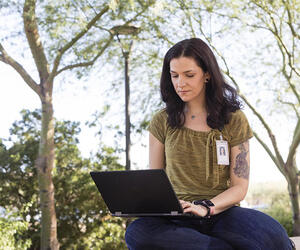 An Associate working on her laptop outside.